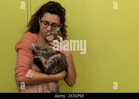 Lateinamerikanische Frau hält sich in den Armen und spielt liebevoll mit ihrer Katze Stockfoto