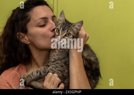 Lateinamerikanische Frau hält sich in den Armen und spielt liebevoll mit ihrer Katze Stockfoto