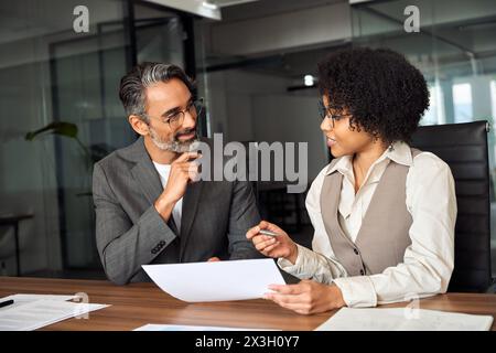 Afrikanische Finanzberaterin berät Klientin Investor beim Lesen des Dokuments. Stockfoto