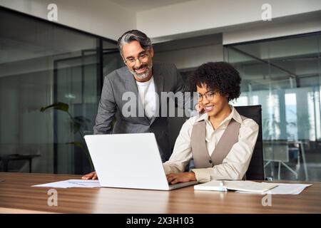 Professionelles Happy Manager Training, das weiblichen Mitarbeitern bei der Computerarbeit hilft. Stockfoto