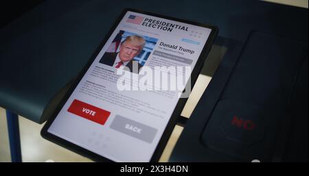 ZAPORIZHYA, UKRAINE - 15. MÄRZ 2024: Wahlkabine mit Tablet-Computer. Informationen über Donald Trump und Schaltflächen auf dem Tablet-Bildschirm. Moderne digitale Technologie für Abstimmungen. Präsidentschaftswahlen in den Vereinigten Staaten von Amerika. Stockfoto