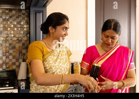 Indische Mutter und Teenager-Tochter kochen zusammen zu Hause in der Küche Stockfoto