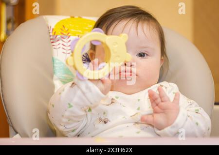 Das Mädchen steht auf dem Stuhl und spielt mit einem Spielzeug Stockfoto