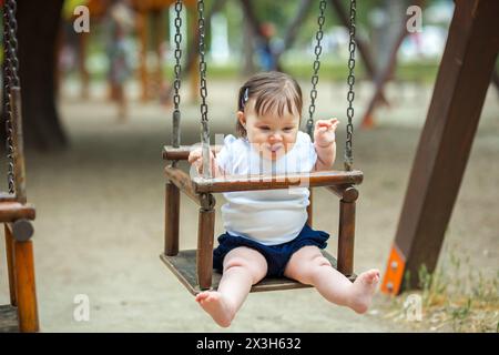 Kleines Mädchen, das in der Wiege im Park schwingt Stockfoto