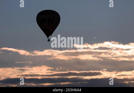 Pfronten, Deutschland. April 2024. Am frühen Morgen gleitet ein Heißluftballon über die Vorberge der Alpen. Quelle: Karl-Josef Hildenbrand/dpa/Alamy Live News Stockfoto