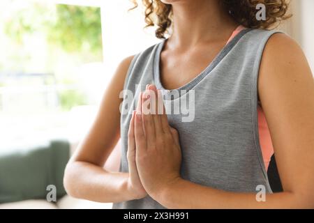 Eine junge kaukasische Frau mit lockigen braunen Haaren, die zu Hause Yoga praktiziert Stockfoto