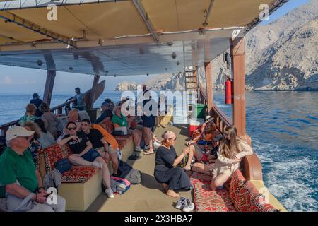 Khasab, Oman - 1. Januar 2024: Touristen an Bord einer traditionellen Dhow erkunden die atemberaubenden Fjorde von Khasab, umgeben von majestätischen Bergen und c Stockfoto