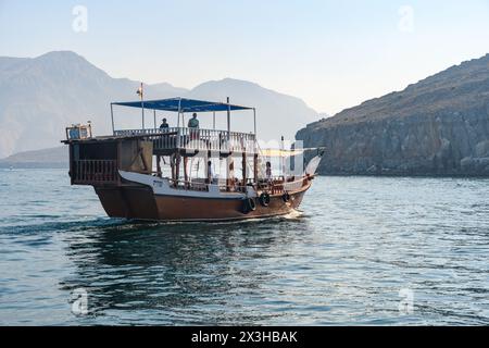 Khasab, Oman - 1. Januar 2024: Touristen begeben sich auf eine ruhige Bootsfahrt und erkunden die atemberaubenden Fjorde von Khasab, wo majestätische Berge auf cryst treffen Stockfoto