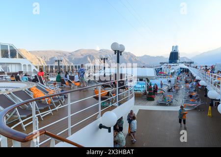 Khasab, Oman - 1. Januar 2024: Während die Sonne untergeht, finden Touristen an Bord eines Kreuzfahrtschiffs im Hafen von Khasab Ruhe in den Abendtönen mit dem majestätischen m Stockfoto