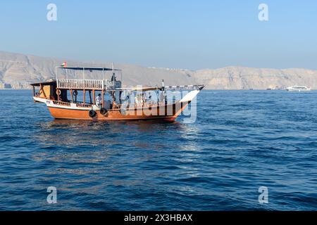 Khasab, Oman - 1. Januar 2024: Touristen an Bord einer traditionellen omanischen Dhow-Kreuzfahrt, bei der sie die ruhigen Gewässer und die atemberaubenden Fjorde von Khasab erkunden. Stockfoto