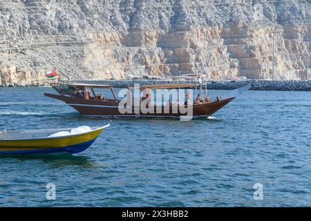 Khasab, Oman - 1. Januar 2024: Touristen an Bord eines traditionellen omanischen Bootes erkunden die majestätischen Fjorde von Khasab, umgeben von zerklüfteten Bergen und Ruhe Stockfoto