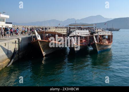 Khasab, Oman - 1. Januar 2024: Ein ruhiger Morgen im Hafen von Khasab, mit traditionellen Holzbooten, die vor der Kulisse der majestätischen Berge angedockt werden Stockfoto