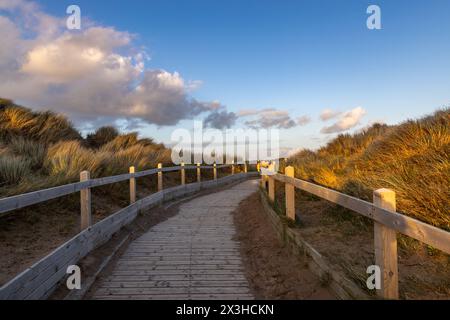 Eine hölzerne Promenade führt an einem sonnigen Abend zum Meer Stockfoto