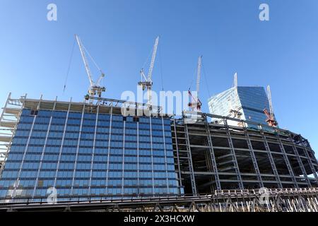 Mehrere Turmkräne bauen einen modernen hohen Wolkenkratzer vor einem klaren blauen wolkenlosen Himmel Stockfoto