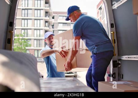 Glückliche Umsteiger, die den Truck mit Gegenständen aus der Bewegung beladen Stockfoto