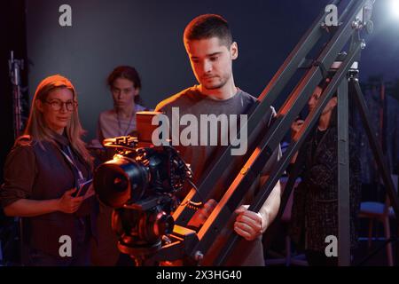 Porträt der Kameramann-Bediengeräte auf dem Bohrgerät im Studio mit roten Neonlichtern im Kopierraum Stockfoto