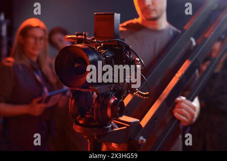 Nahaufnahme eines Kameramanns, der eine Videokamera im Studio mit roten Neonlichtern im Kopierraum bediente Stockfoto