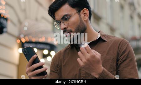 Nahaufnahme aufgebracht unglücklicher indischer arabischer ethnischer Mann junger Mann Geschäftsmann männlich mit aussehendem Handy schlechte Verbindung Verlust Vermögen Verlust Fail Touch Stockfoto