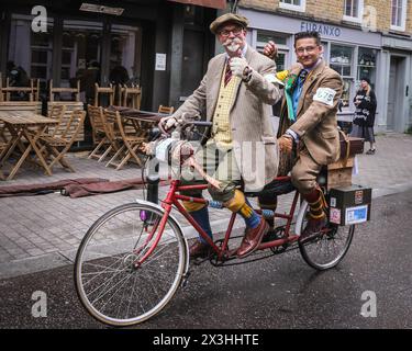 London, Großbritannien, 27. April 2024. Ein Tandemfahrrad mit zwei Herren auf einer Mission zu fahren. Die Teilnehmer fahren durch den Exmouth Market. Der Tweed Run ist eine Fahrradtour durch die historischen Straßen Londons, wobei die Teilnehmer ihre besten Tweed- und stilvollen Fahrradbekleidung tragen müssen. Sie wird von Bourne & Hollingsworth organisiert und wurde 2008 mit nur einer kleinen Gruppe von Freunden gegründet, die rund 800 Radfahrer durch das Zentrum von London fahren. Dieses Jahr beginnt die malerische Route in Clerkenwell mit Pausen an einigen der schönsten Wahrzeichen und versteckten Schätzen der Stadt. Die Teilnehmer können einen gemütlichen Tag c erwarten Stockfoto