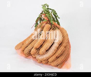 Ein Sack Tamarindenfrüchte mit grünen Blättern auf weißem Hintergrund. Bündel von Tamarindus indica. Stockfoto