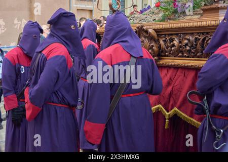 Tarragona, Spanien - 27. April 2024: Gruppe von Personen, die an einer Karwoche-Prozession teilnehmen. Stockfoto