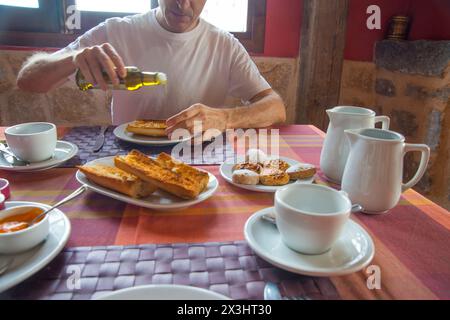 Mann, der beim Frühstück Olivenöl auf Toast gießt. Stockfoto