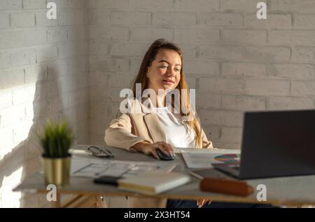 Momentaufnahme des Erfolgs, als eine lebendige junge Geschäftsfrau lächelt, die voll mit ihrer Arbeit in einem modernen Büro beschäftigt ist Stockfoto