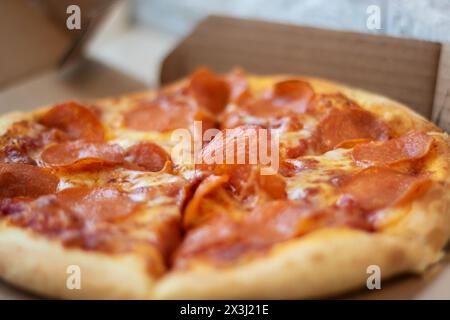 Eine Pepperoni-Pizza, ein Grundnahrungsmittel in der Fast-Food-Küche, liegt in einem Karton. Dieses Backwarengericht ist ein klassisches Rezept für kalifornische Pizza Stockfoto