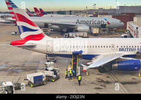 London, England, Großbritannien - 29. November 2023: Flughafenarbeiter, die Gepäck aus einem Flugzeug von British Airways am Flughafen London Heathrow entladen. Stockfoto