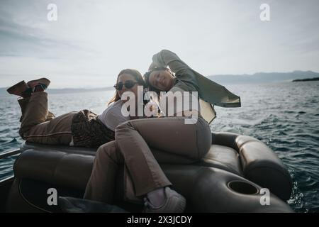 Freunde, die eine unbeschwerte Bootsfahrt auf einem See genießen und sich in der Freude der gemeinsamen Entspannung erfreuen Stockfoto