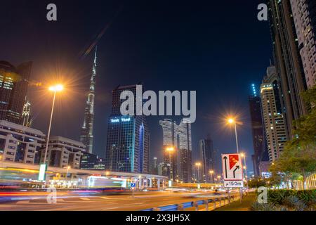 Lange Sicht auf die Skyline von Dubai bei Nacht, mit dem Burj Khalifa mit Ampelpfaden auf der Sheikh Zayed Road, VAE. Stockfoto