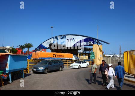 Autos parkten neben dem Zugang zum Fischereihafen, LKW fahren in den kommerziellen Hafen Terminal im Hintergrund, Arica, Chile Stockfoto