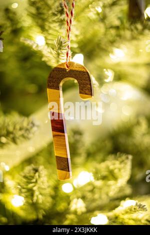 Ein hölzernes Ornament in Form eines Bonbons aus mehreren Holzarten hängt an einem Weihnachtsbaum Stockfoto