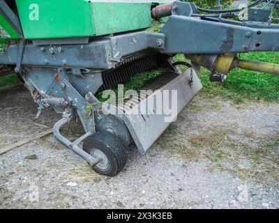 Partielle Ansicht der Zinken der Zapfwellenfeder und der Aufnahmerolle einer Ballenpresse auf einer Schotteroberfläche nach intensivem Einsatz. Stockfoto