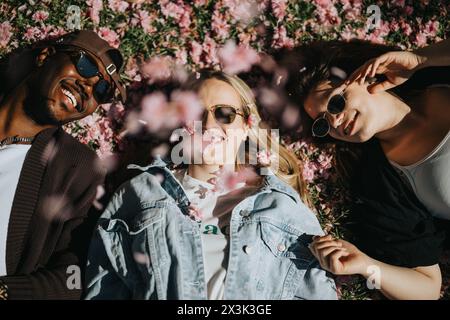 Drei Freunde genießen einen sonnigen Tag mit Lachen zwischen rosa Kirschblüten Stockfoto