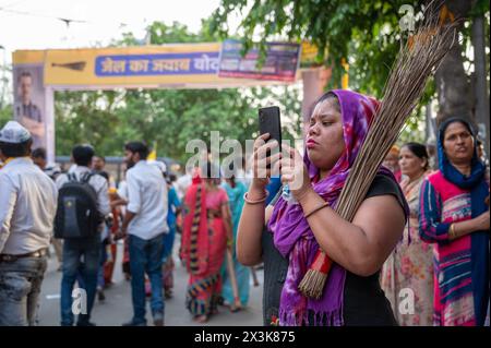 Neu-Delhi, Indien. April 2024. Eine weibliche Unterstützerin der AAM-Aadmi-Partei hält das Symbol der Partei, einen Besen, während sie an einer Roadshow unter der Leitung von Arvind Kejriwals Frau Sunita Kejriwal in Kalyan Puri im Wahlkreis Ost-Delhi teilnimmt. Die AAM Aadmi Party (AAP) führt eine Roadshow vor den Wahlen in Lok Sabha durch. Die AAM Aadmi Party ist eine politische Partei in Indien und derzeit die Regierungspartei im indischen Staat Punjab und im unionsgebiet Delhi. Quelle: SOPA Images Limited/Alamy Live News Stockfoto