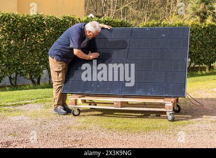 Senior Mann mit Photovoltaik-Solarmodul im Garten. Stockfoto