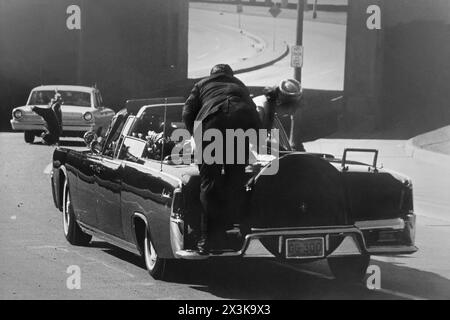 Präsident John F. Kennedy sackte am 22. November 1963 in Dallas, Texas, auf den Rücksitz seines Autos. First Lady Jaqueline Kennedy lehnt sich über den Präsidenten, während ein Geheimdienstmann ihr zu Hilfe kommt. (USA) Stockfoto