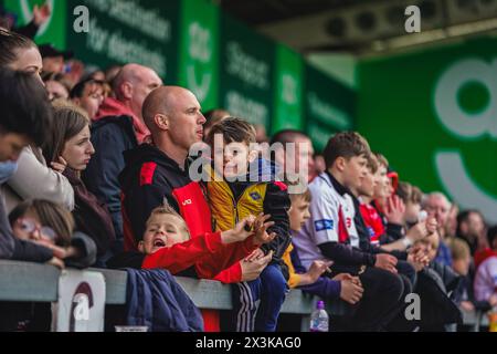 Salford, Manchester, Großbritannien. April 2024. Superliga Rugby: Salford Red Devils gegen Warrington Wolves im Salford Community Stadium. Ein junger Salford-Fan mit seinem Vater in der Menge. James Giblin/Alamy Live News. Stockfoto