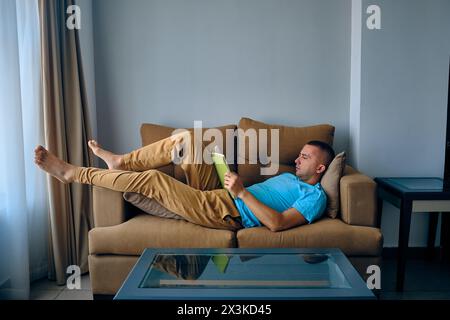 Ein Mann liest ein Buch, das auf dem Sofa liegt Stockfoto
