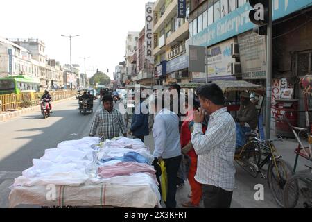 Dehli, Indien, 6. März 2019: Straßenverkäufer, der Kleidung und weiße Stoffe in der belebten Straße von Old Dehli mit mobilem Verkaufsstand verkauft. Stockfoto