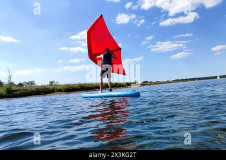 21. April 2024: Mann surft mit einem Flügelboot oder Windsegel auf einem SUP Board oder aufblasbarem Surfboard mit dem Wind im Wasser auf einem Badesee bei Sonnenschein *** Mann surft mit einem Wingfoil bzw. Wind-Segel auf einem SUP Board bzw. Aufblasbares Surfbrett mit dem Wind im Wasser auf einem Badesee bei Sonnenschein Stockfoto