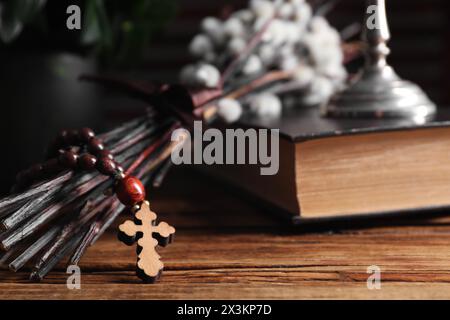 Rosenkranzperlen, Bibel und Weidenzweige auf Holztisch, Nahaufnahme Stockfoto