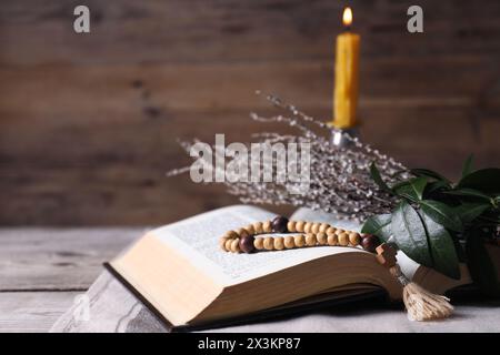 Rosenkranzperlen, Bibel und Weidenzweige auf dem Tisch, Nahaufnahme Stockfoto