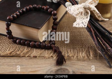 Rosenkranzperlen, Bibel und Weidenzweige auf Holztisch, Nahaufnahme Stockfoto