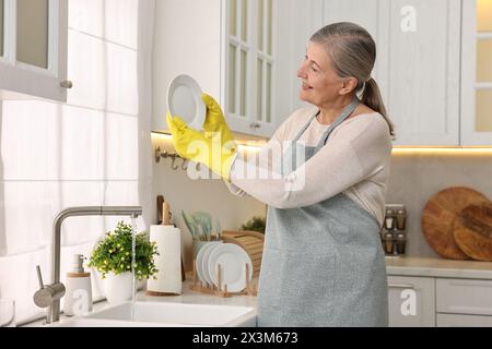 Glückliche Hausfrau Waschplatte in Küchenspüle Stockfoto