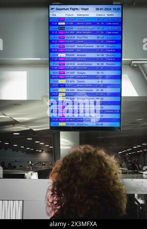 Frau, die auf die Fluginformationstafel schaut, überprüft ihren Flug im internationalen Flughafen Mumbai Indien-26.März 2024, Ankunft, Abfluginformationen Stockfoto