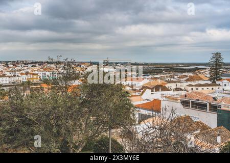 Panoramablick auf Tavira, Portugal, mit einer Mischung aus traditioneller und moderner Architektur, mit orange gefliesten Dächern und Küstenlandschaft. Stockfoto