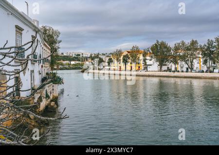 Tavira, Portugal, 8. Januar 2024. Blick auf den Fluss in Tavira, Portugal, mit weiß getünchten Gebäuden, Laubbäumen und Reflexen im ruhigen Wasser Stockfoto