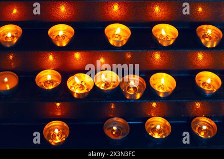 Teelichterkerzen brennen in der Kirche. Kerzen beleuchten den heiligen Raum sanft. Warmes Ambiente Stockfoto
